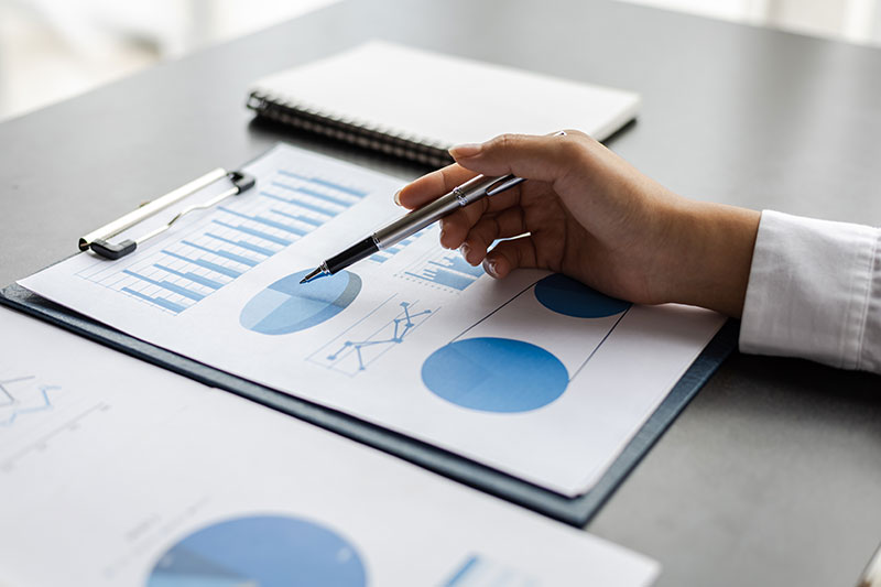 Person holding a pen over a pie chart